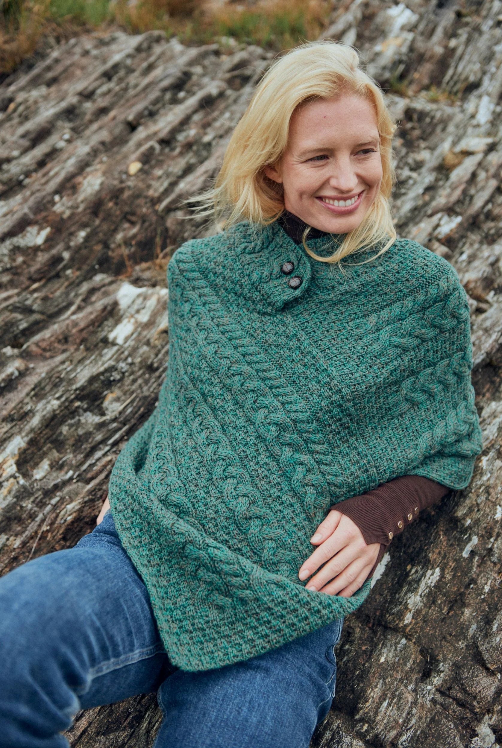 Close-up of Connemara green merino wool Aran poncho showing wooden buttons and textured cable knit pattern.