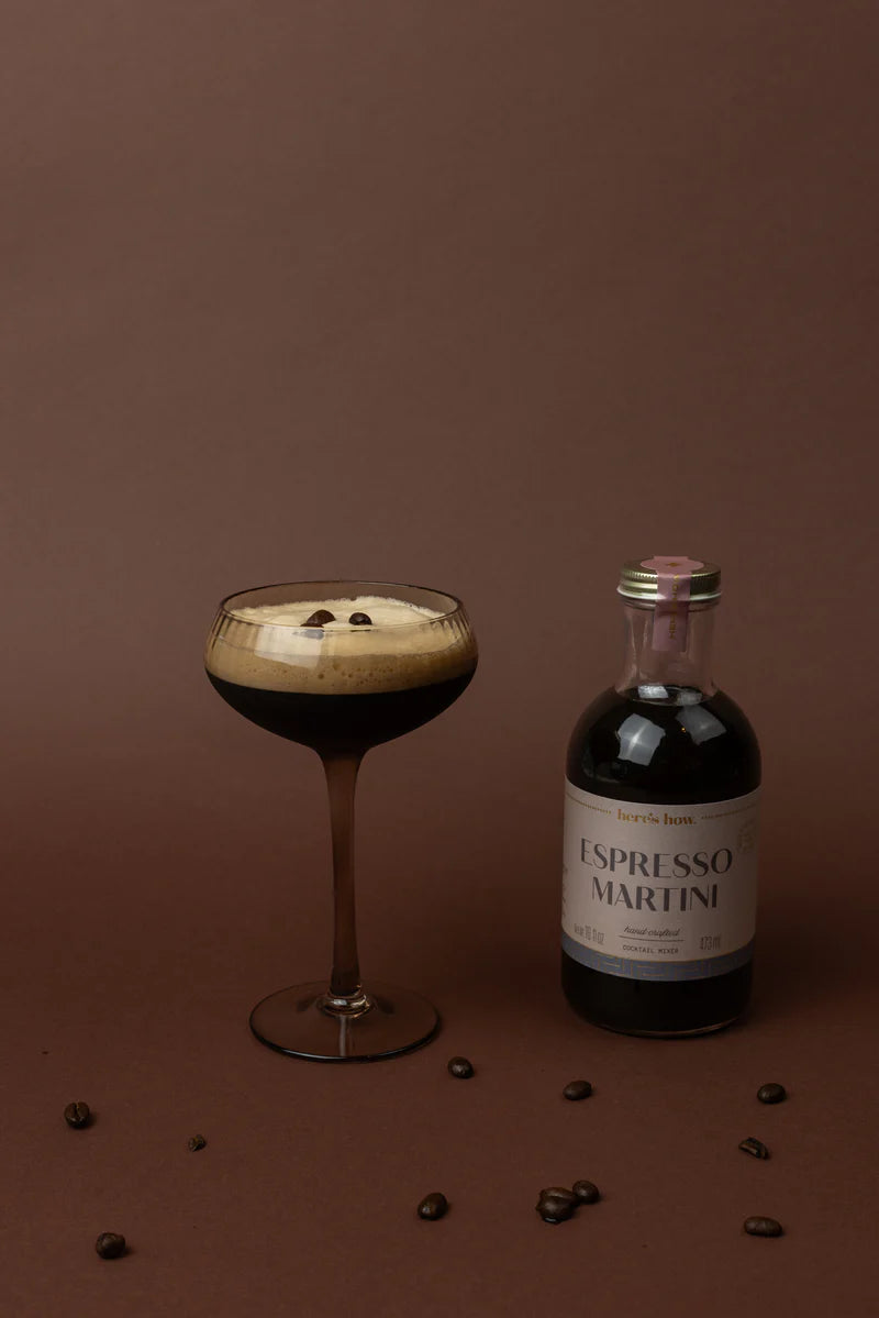 An espresso martini cocktail with a bottle of th Here's How cocktail mixer
