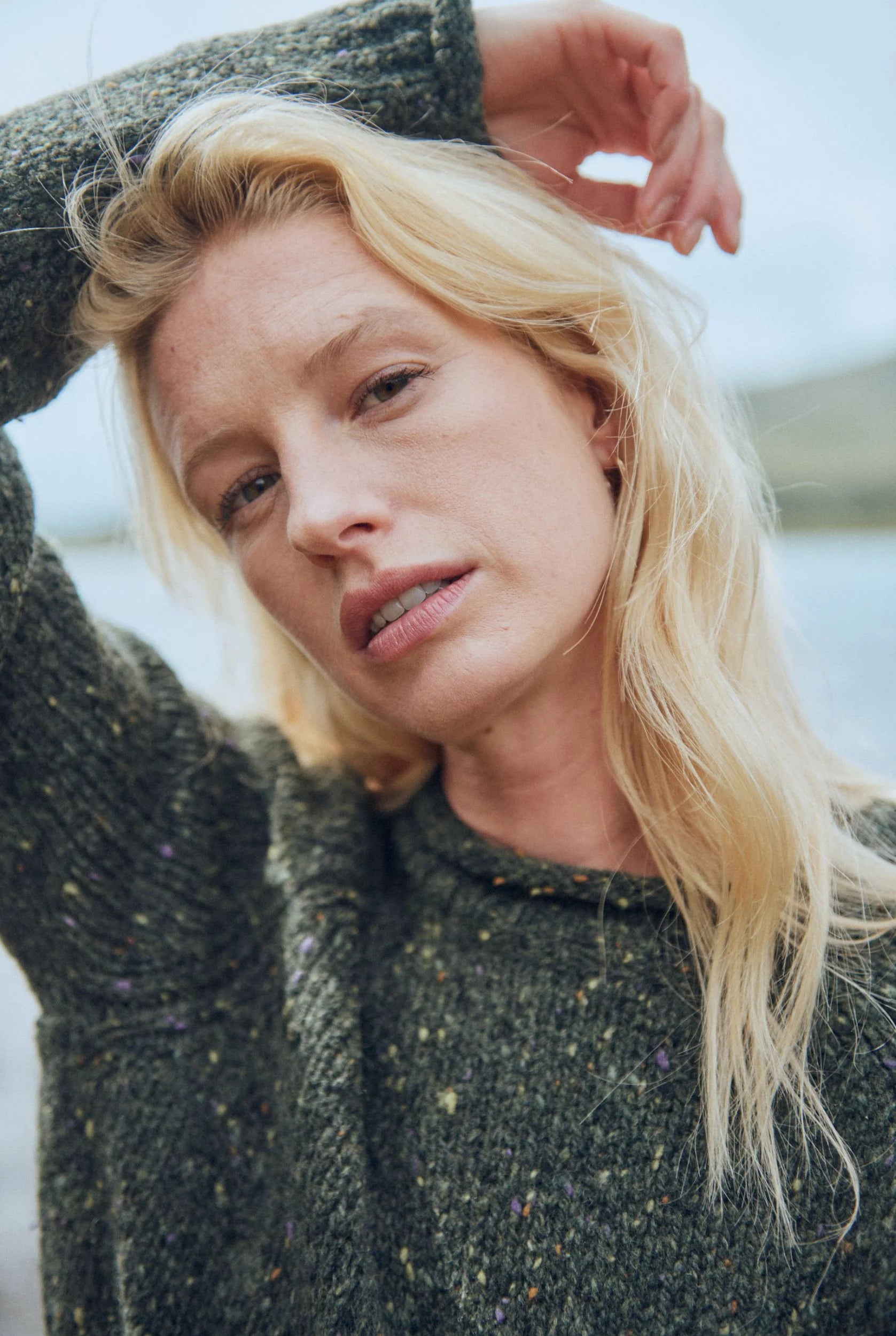 Outdoor view of Brackloon Tweed Roll Neck Aran Sweater in deep forest green, relaxed fit with rolled hem.