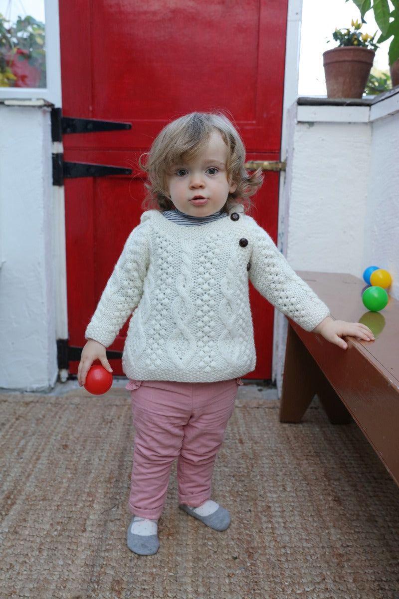 Baby modelling Aran Woolen Mills baby hoodie in natural