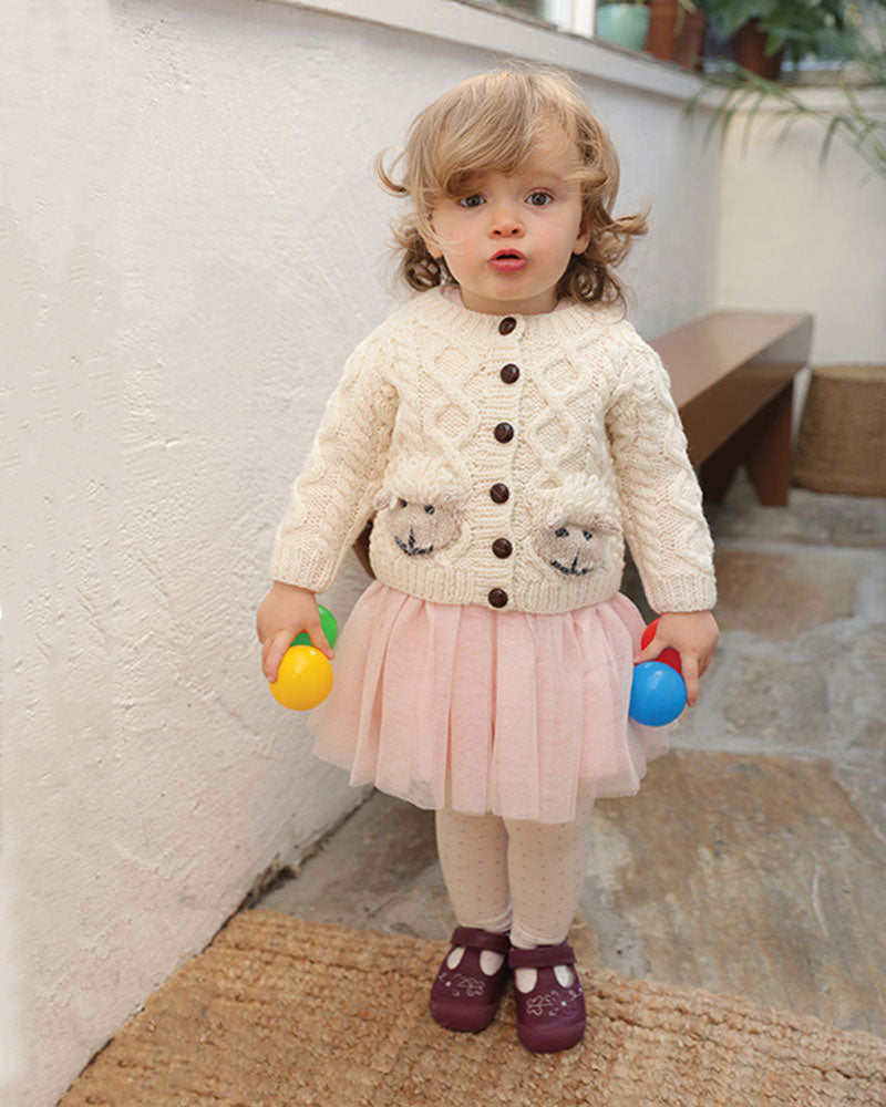 Baby modelling Aran Woollen Mills handknit wool cardigan sweater with sheep pockets