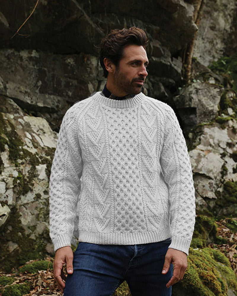 Model wearing an Aran handknit crew neck sweater in a natural colour