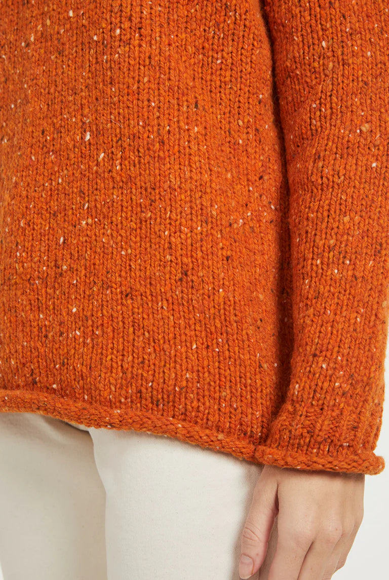 Close-up of Brackloon Tweed Roll Neck Aran Sweater in burnt orange, showing nepped Donegal tweed yarn texture.