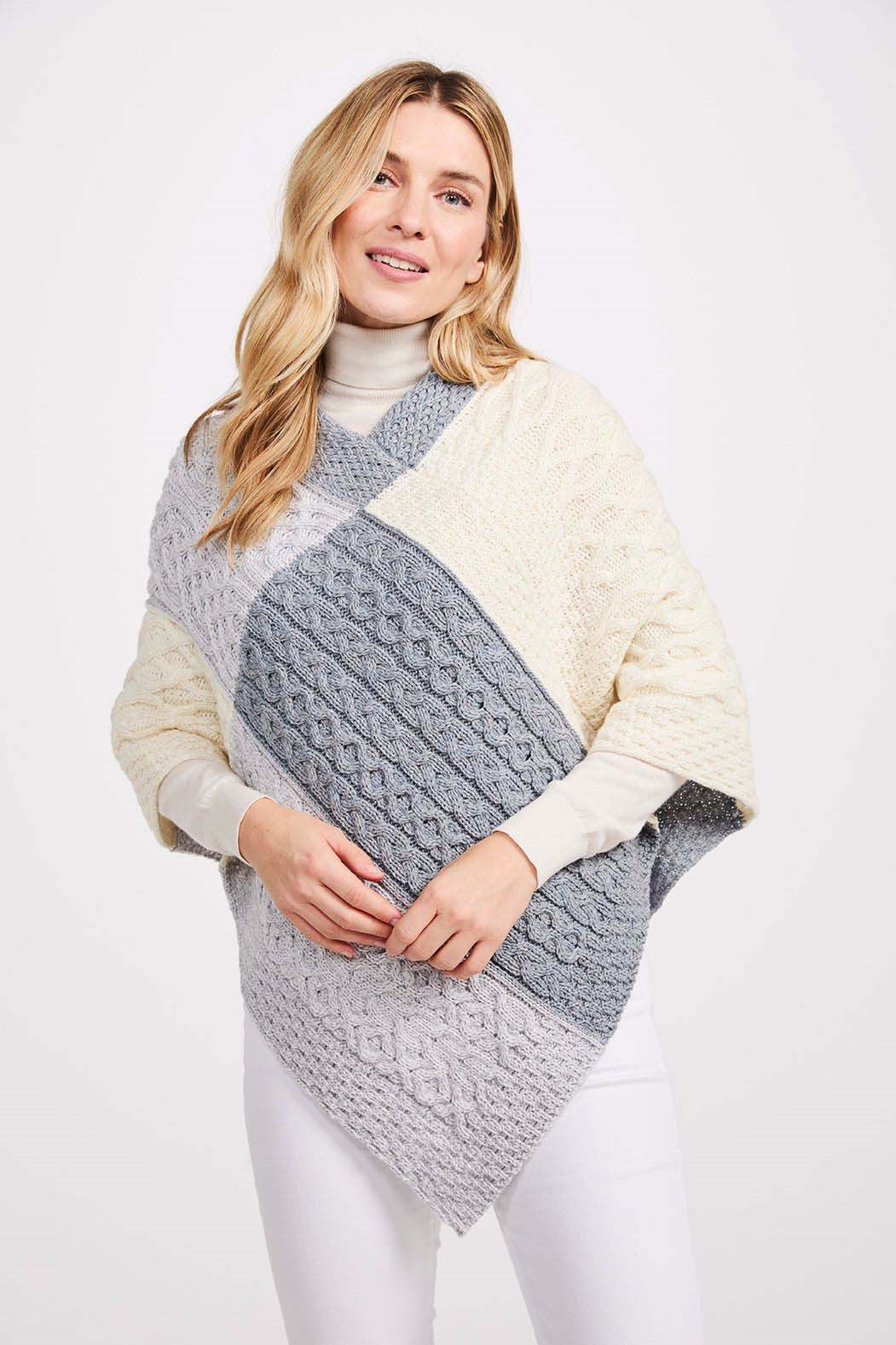 Model wearing grey Aran Woollen Mills patchwork poncho with traditional cable and honeycomb stitches.