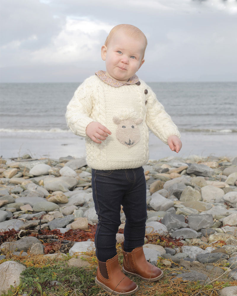 Baby modelling an Aran crew neck hoodie with a sheep motif in the centre