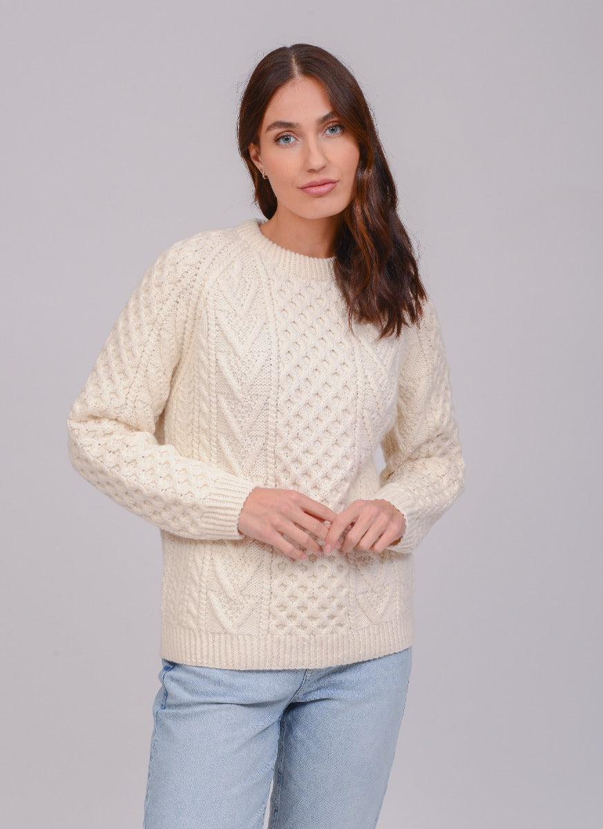 Model wearing an Aran handknit crew neck sweater in a natural colour